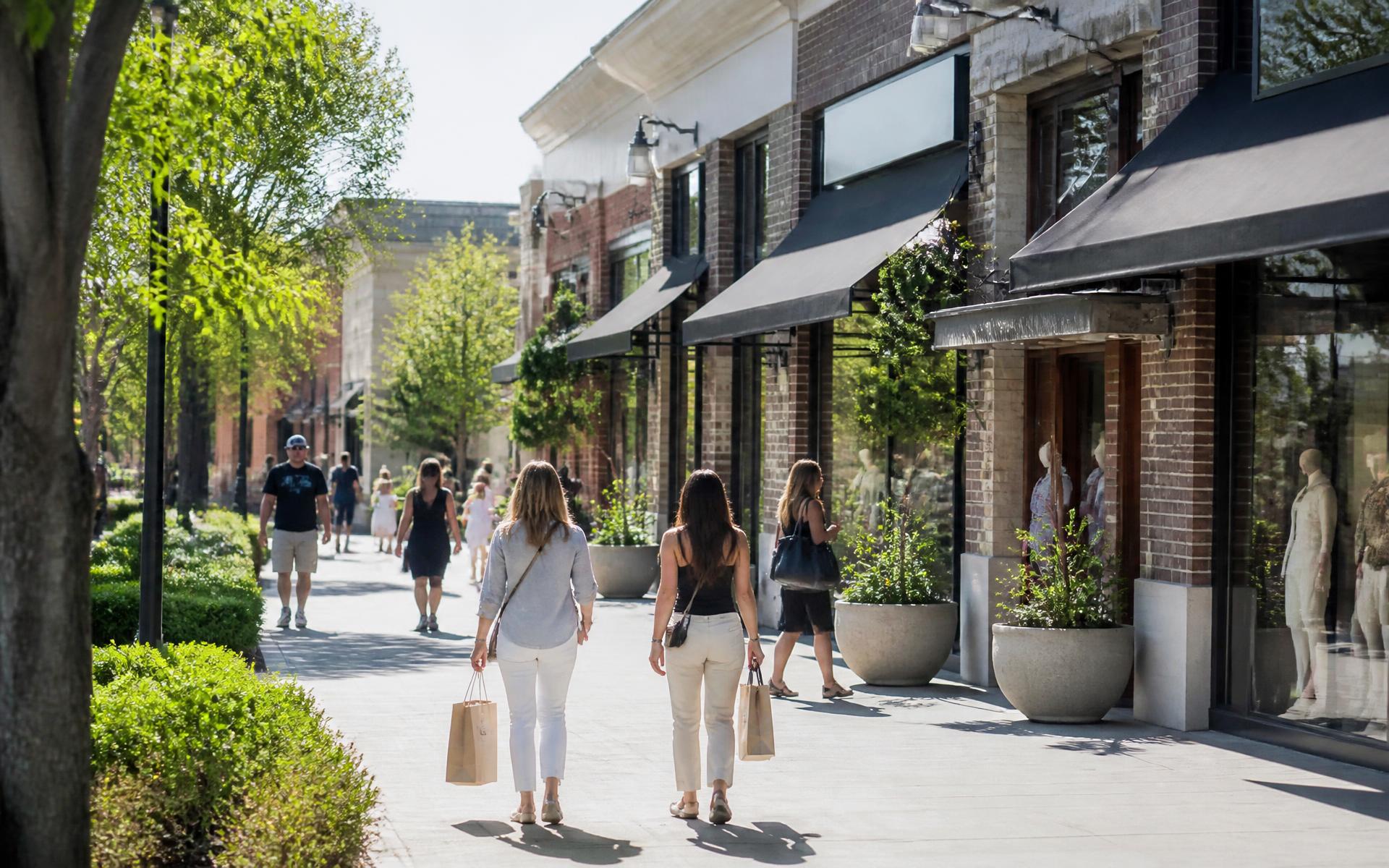 Storefronts and planters along a shopping village sidewalk